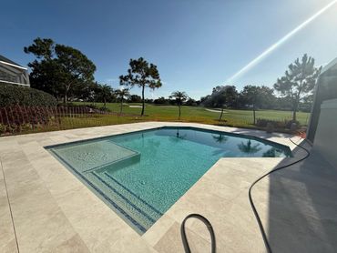 A clean, modern swimming pool with a tiled deck on a sunny day.