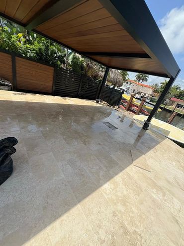 A shiny tiled patio with a shaded pergola and waterfront view.