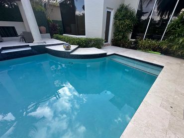 A clean backyard pool with clear blue water and surrounding patio.