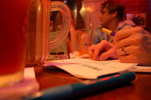 Person filling out a trivia sheet at a bar.