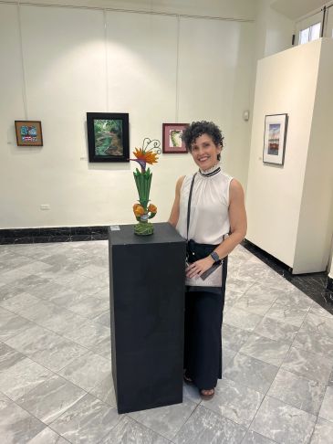 Woman posing beside a flower sculpture in an art gallery.