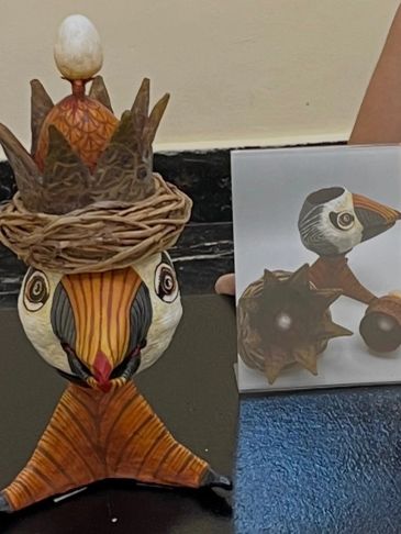 Artistic wooden bird sculpture with crown and sphere detail.