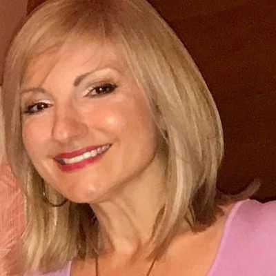 Smiling woman with blonde hair and hoop earrings.