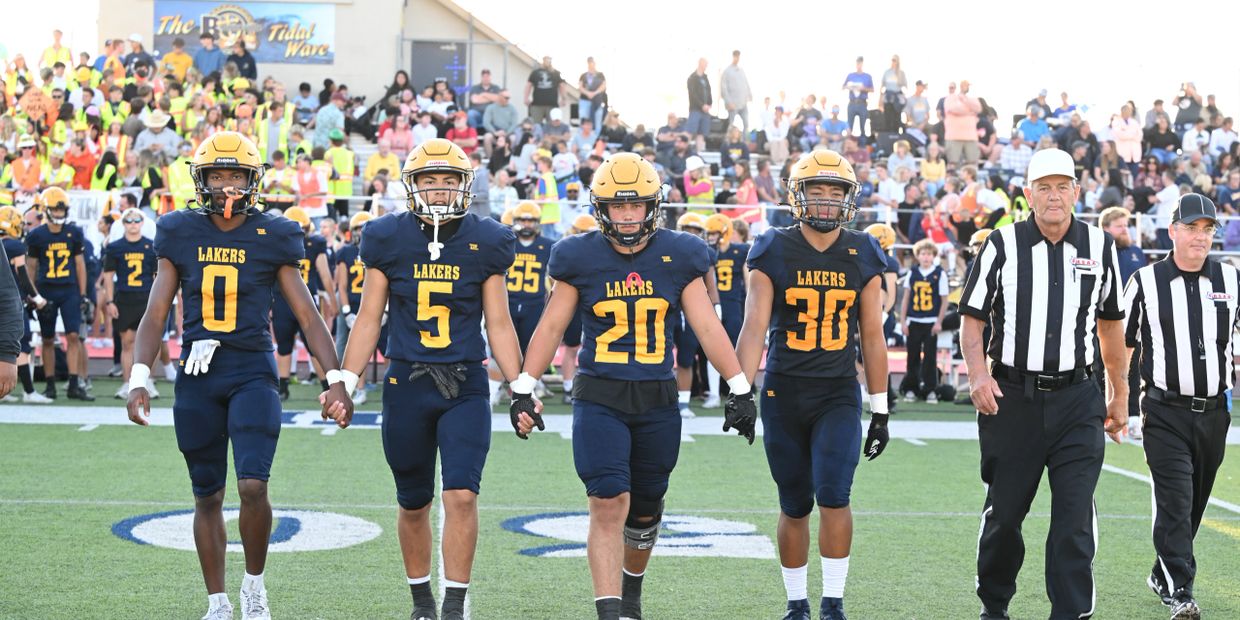 High school football captains and referees walking together before the game.