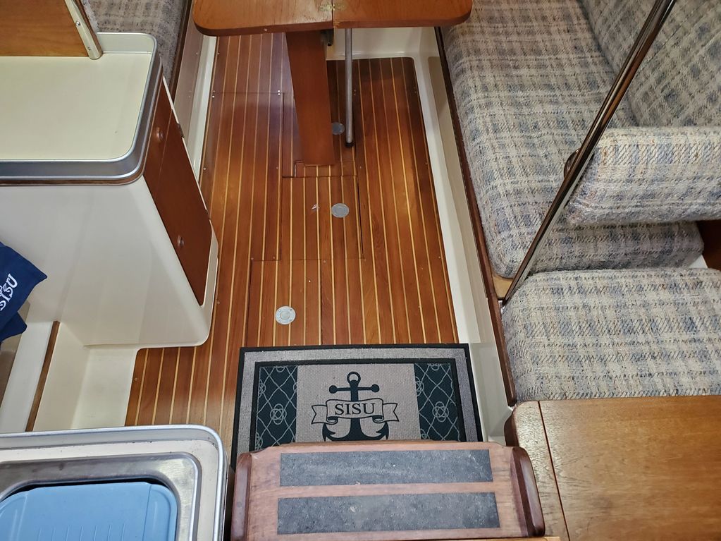 Interior of a boat with wooden flooring and cushioned seating.