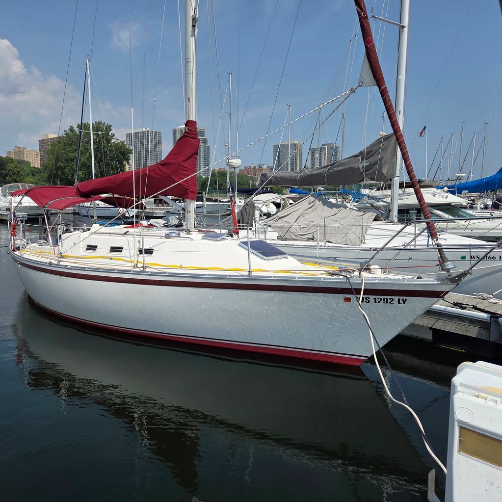 Sailboat docked at a marina with city buildings in the background.