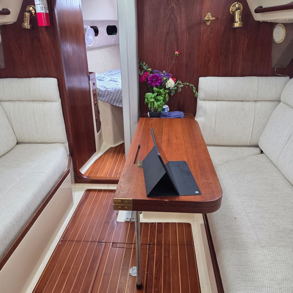 Cozy boat interior with wooden table, cushioned seats, and a floral arrangement.