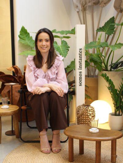 Mulher sentada com roupas elegantes em ambiente decorado.