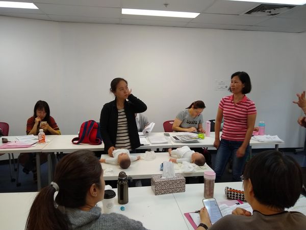 Adults participating in a baby care training session with infant dolls.