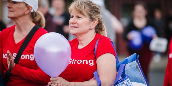Woman in red holding a purple balloon at an event.