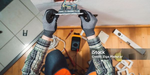 Electrician repairing a wall socket with tools around.