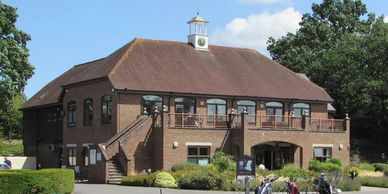 A brick building with a clock tower and bicycles parked outside.