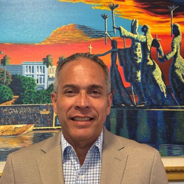 Man smiling in front of colorful mural.