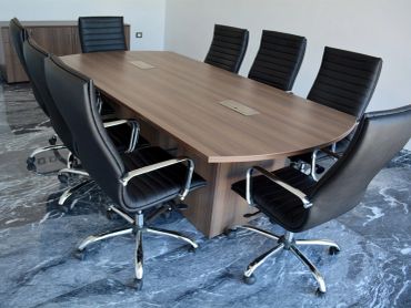 Modern conference room table with black office chairs on marble flooring.