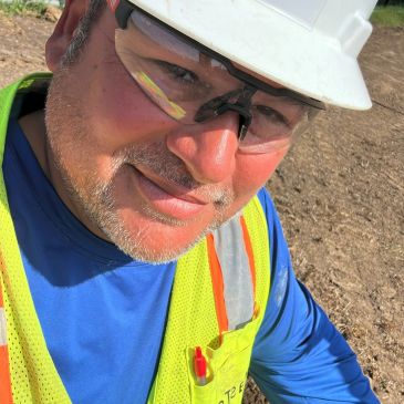 Man wearing safety glasses and helmet outdoors.