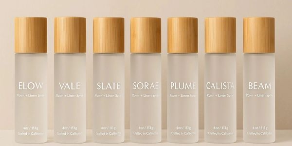 Seven frosted glass room and linen sprays with wooden caps.