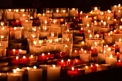 Many lit candles in glass holders.