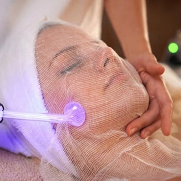Woman receiving a facial treatment with a mesh covering.