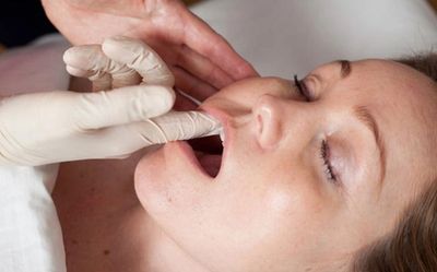 Person receiving an oral examination by a gloved professional.