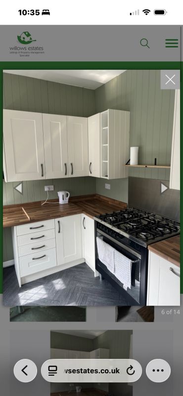 Compact kitchen with white cabinets and wooden countertops.