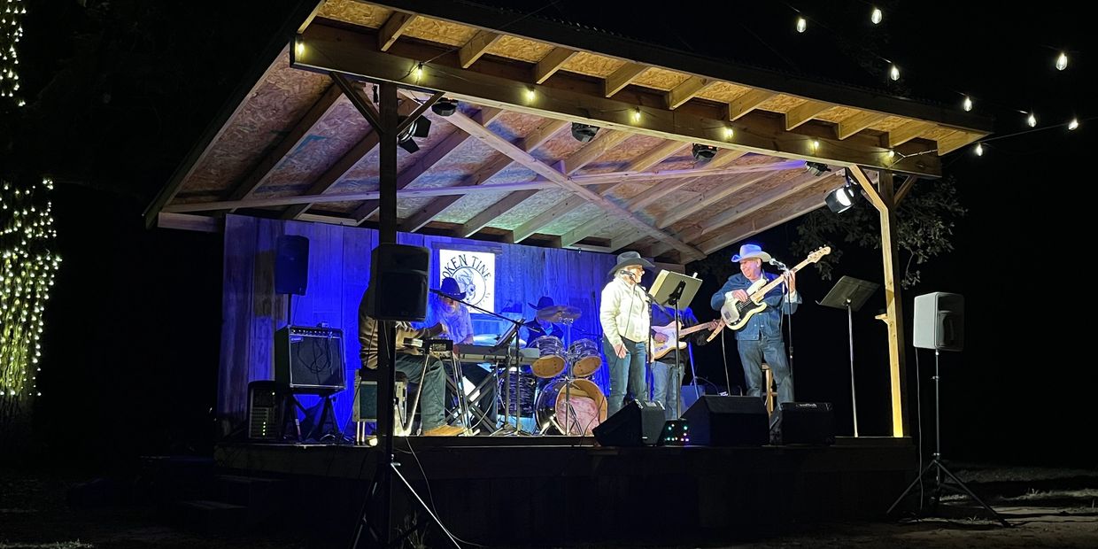 Band performing on a small outdoor stage at night.