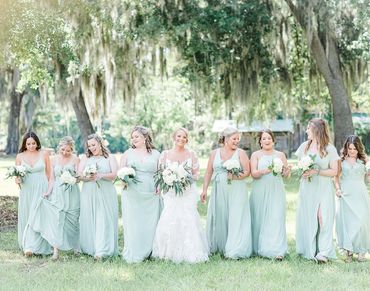 Bride with bridesmaids in light green dresses walking outdoors.