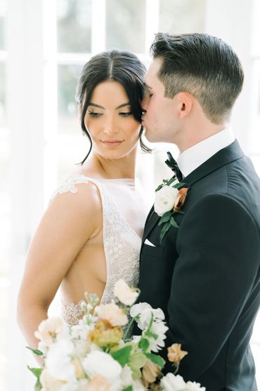 Groom tenderly kisses bride on the temple during their wedding.