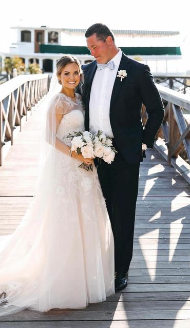 Bride and groom posing on a wooden bridge during their wedding day.