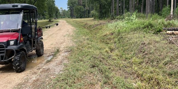 Utility vehicle parked on a dirt trail in a forested area.