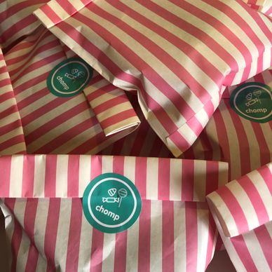 Pink and white striped candy bags sealed with green "chomp" stickers.
