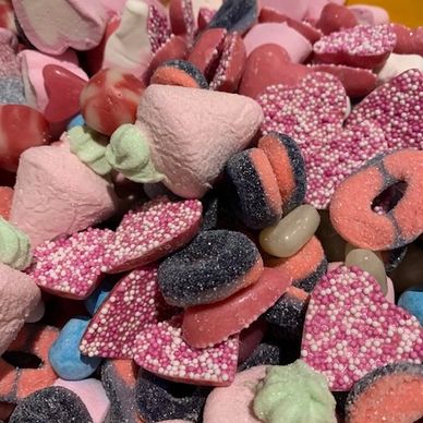 Colorful assortment of heart-shaped and round candies with sugar coatings.
