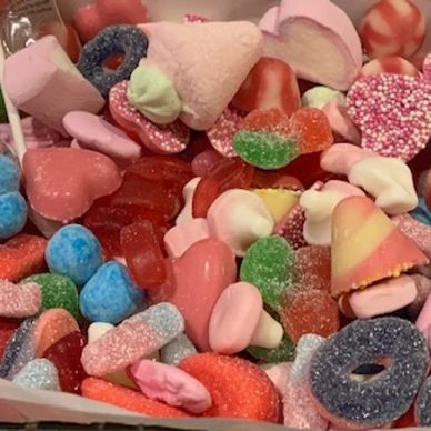 A colorful mix of assorted gummy and marshmallow candies in pink, red, blue, and green.