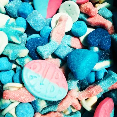 Close-up of colorful assorted gummy candies in blue, pink, and white hues.
