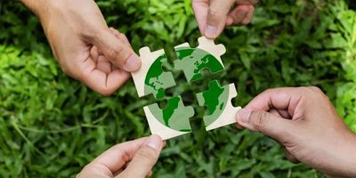 Hands assembling a green earth puzzle.