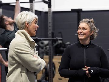 Two women chatting and smiling in a gym setting.