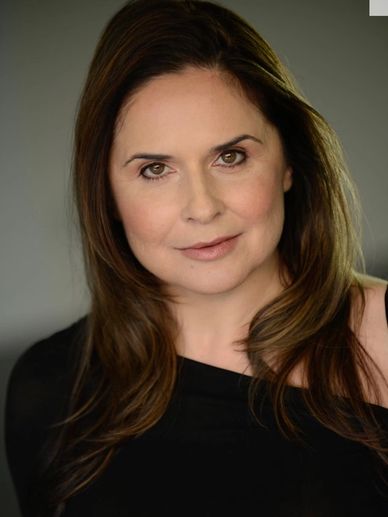 Portrait of a confident woman with brown hair and a subtle smile.