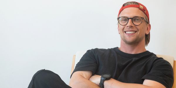 Smiling man in glasses and red cap sitting relaxed in a chair.