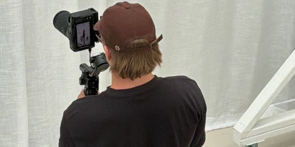 A person in a brown cap filming with a camera in a studio.