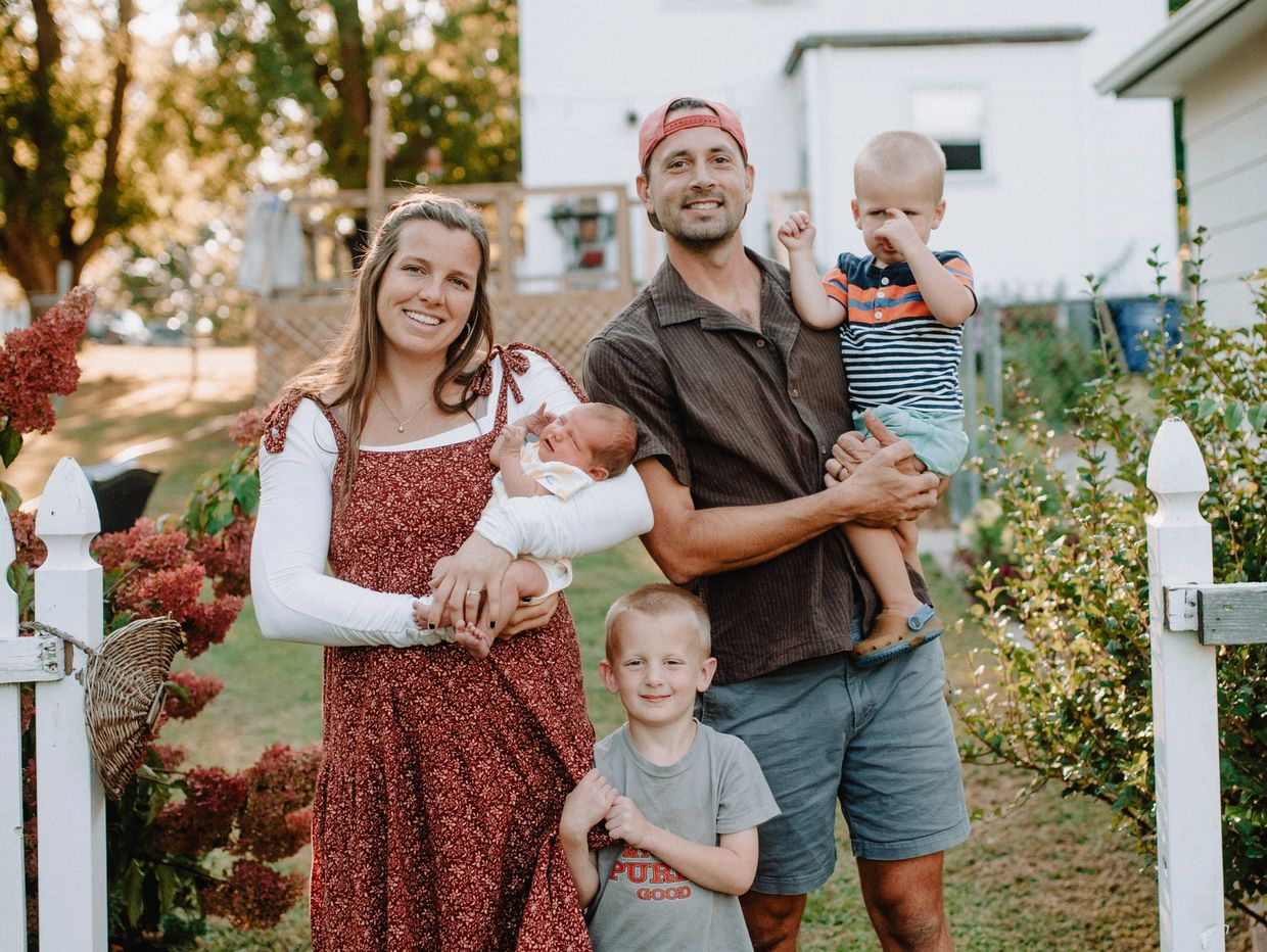 Happy family portrait outdoors with parents and three young children.