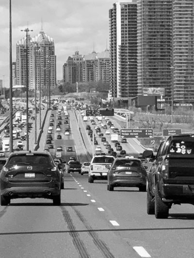 Busy highway traffic with city buildings in the background.