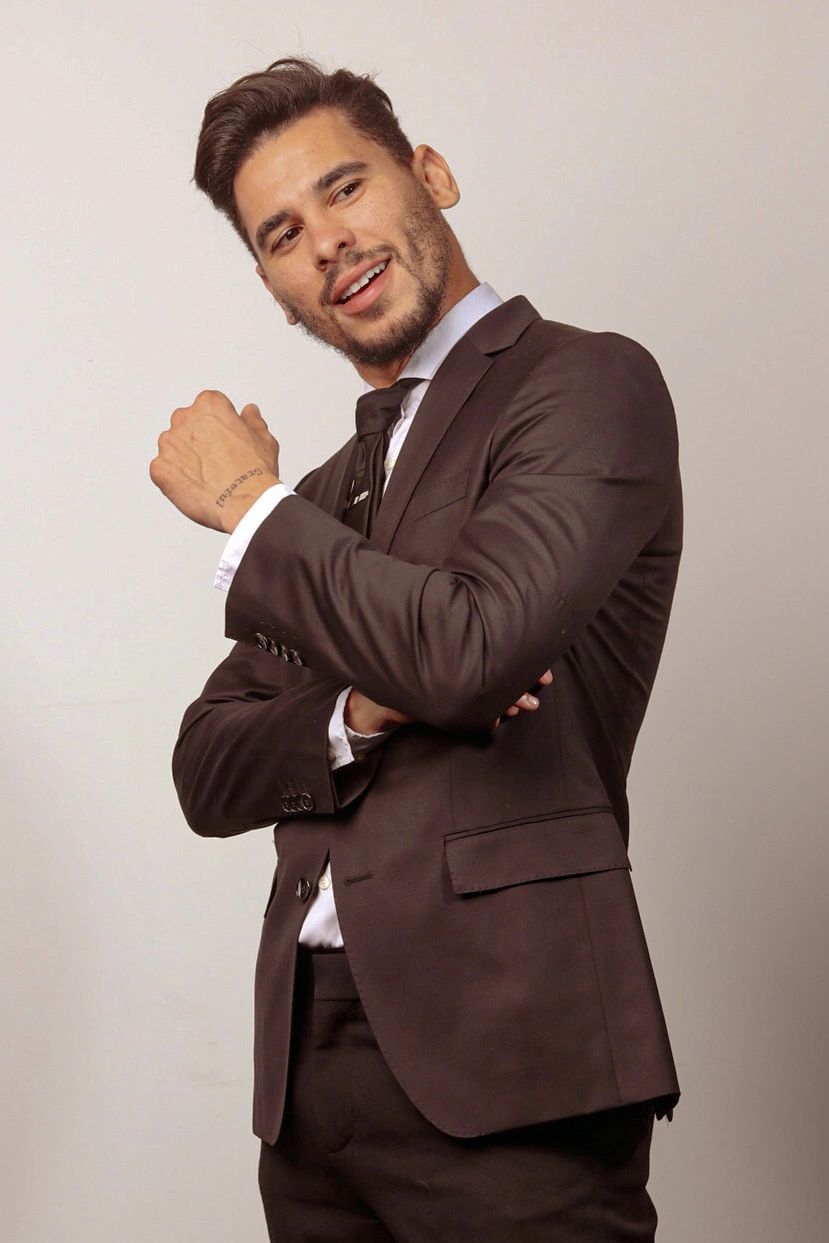 Man in a dark suit smiling confidently.