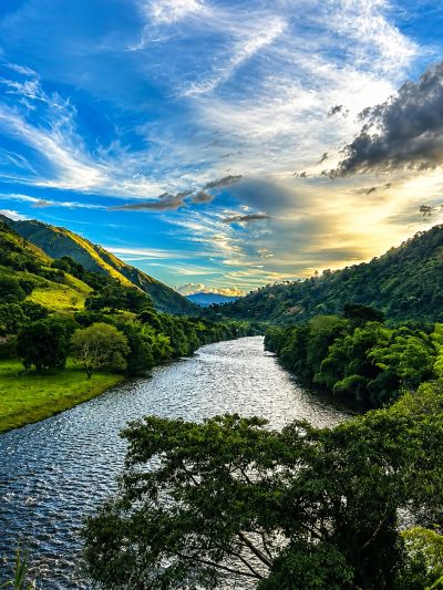 River flowing between green hills under a partly cloudy sky.