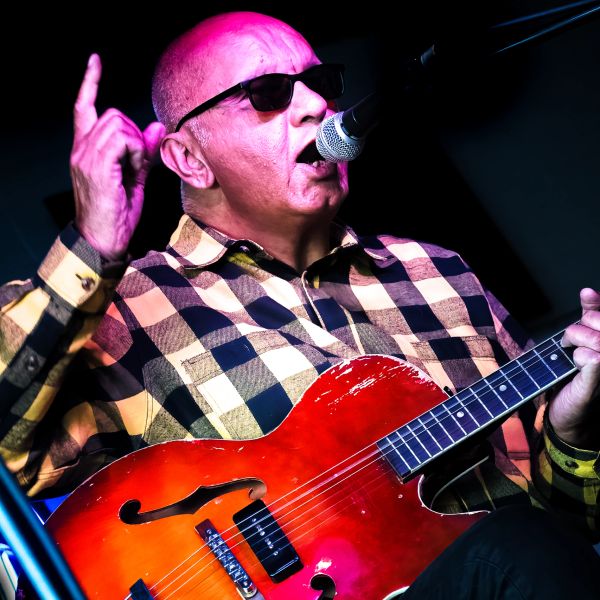 Man singing and playing guitar on stage.