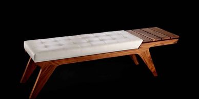 Elegant wooden bench with cushioned seat and side table.