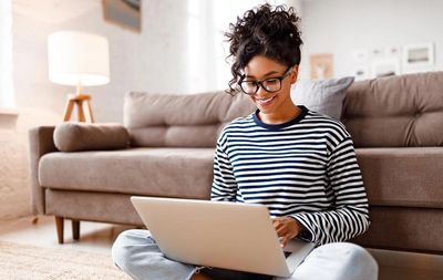 Young woman smiling while using a laptop at home.