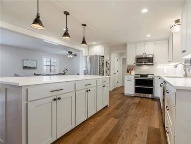 Modern white kitchen with wooden floor.