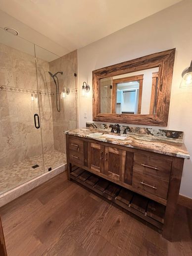 Rustic bathroom with wooden vanity and glass shower.