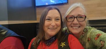 Two women smiling for a close-up selfie indoors.