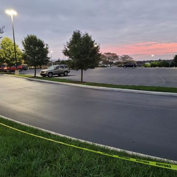 Parking lot at dusk with caution tape along the grass.