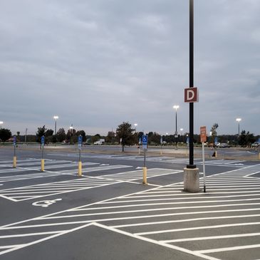 Empty parking lot with designated handicapped spaces under cloudy sky.